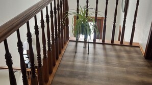 Una escalera de madera con barandilla, una planta en maceta y un candelabro.