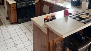 Una cocina con gabinetes de madera, microondas, estufa y lavaplatos.