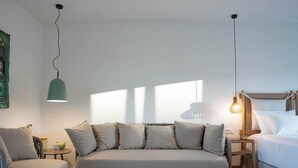 Une chambre à coucher moderne avec un grand lit, un canapé, une petite table ronde et un luminaire suspendu.