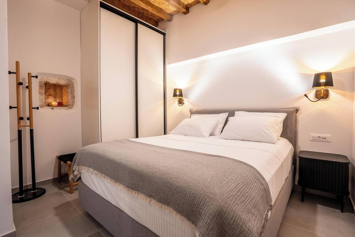 Un dormitorio con cama, mesitas de noche y lámparas de pared.