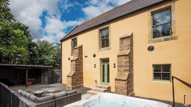 A house with a hot tub, outdoor seating, and a stone facade.
