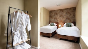 A hotel room with two beds, a wooden headboard, a robe rack, and a textured wall.