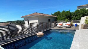 A rectangular swimming pool with a wooden deck and a tiled border. - Superb villa with pool (Unknown)