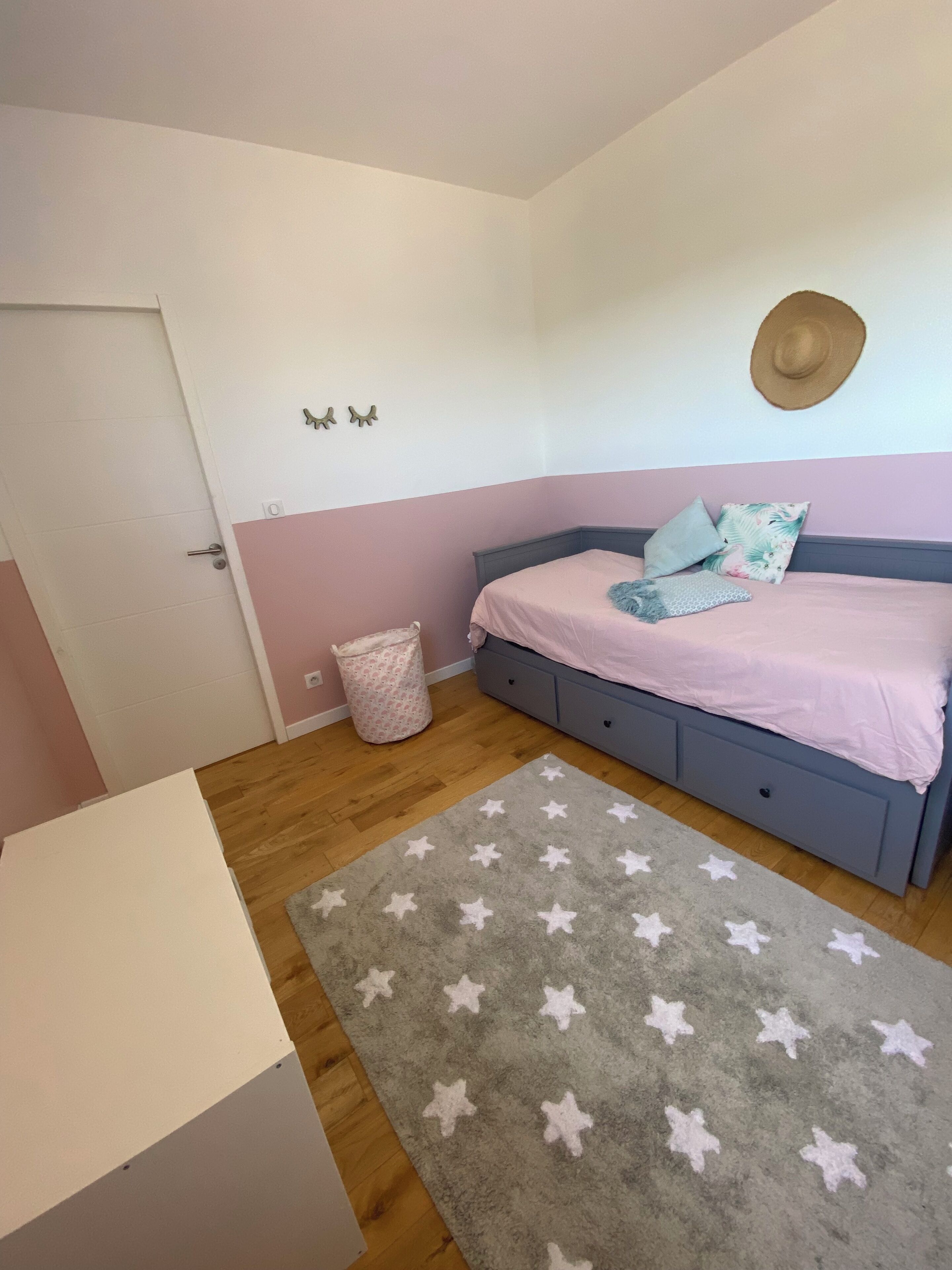 Ein Schlafzimmer mit einem Bett, einem Nachttisch, einer Mülleimer und einem Teppich mit Sternenmuster.