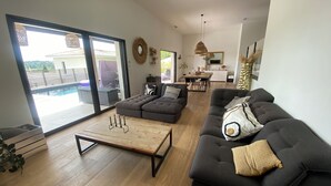 A spacious living room with a large sectional sofa, a wooden coffee table, and a dining area in the background. - Superb villa with pool (Unknown)