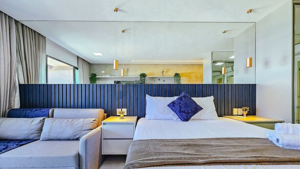 A modern hotel room with a large bed, two bedside tables, a sofa, and a large mirror. - Art Studio by VLV Stays (Salvador)