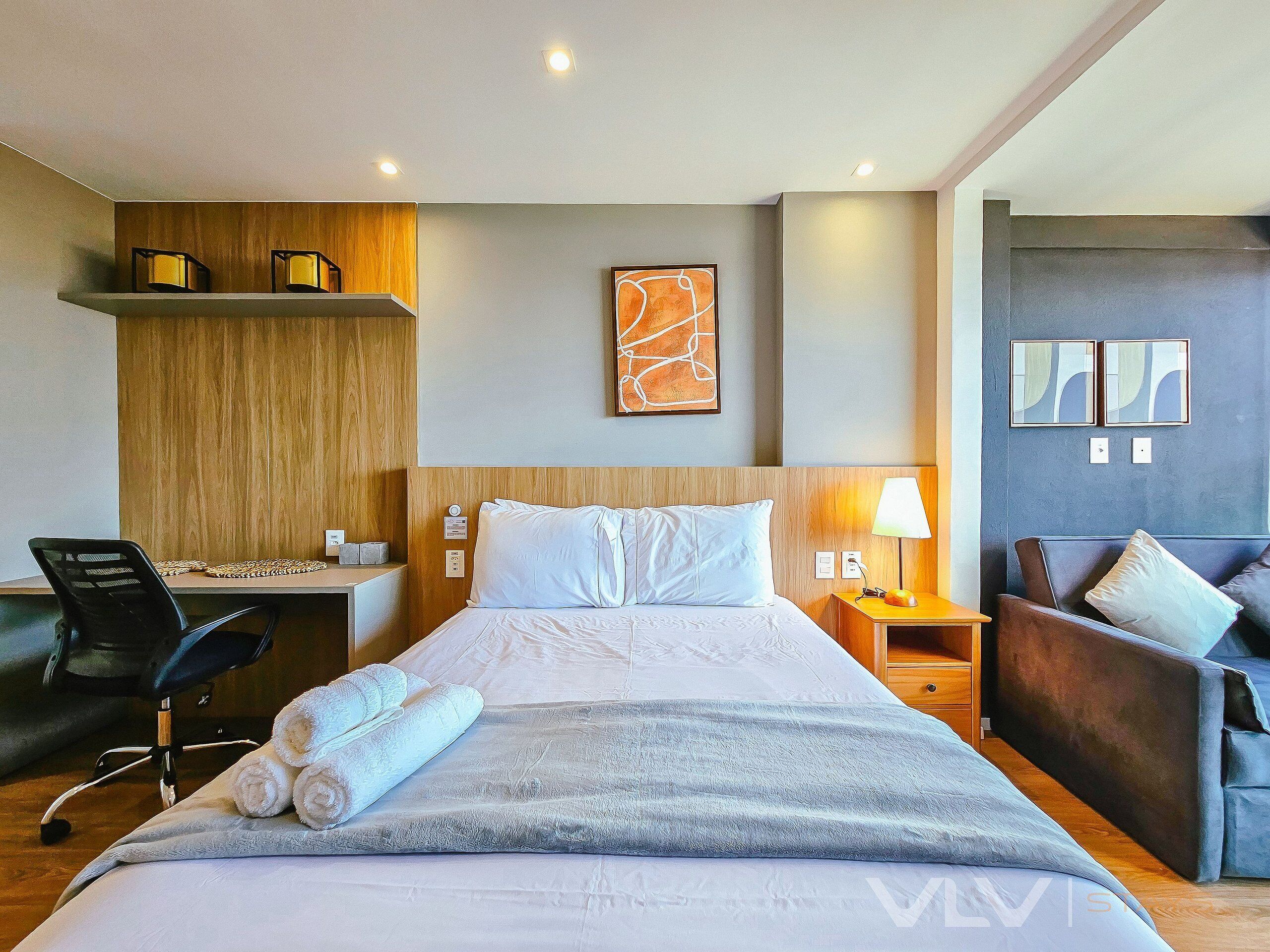 Een hotelkamer met een bed, een bureau, een stoel en een bank.