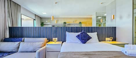 A modern hotel room with a large bed, two bedside tables, a sofa, and a large mirror.
