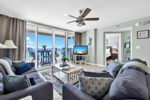A living room with a sofa, coffee table, TV, and a balcony with a view.