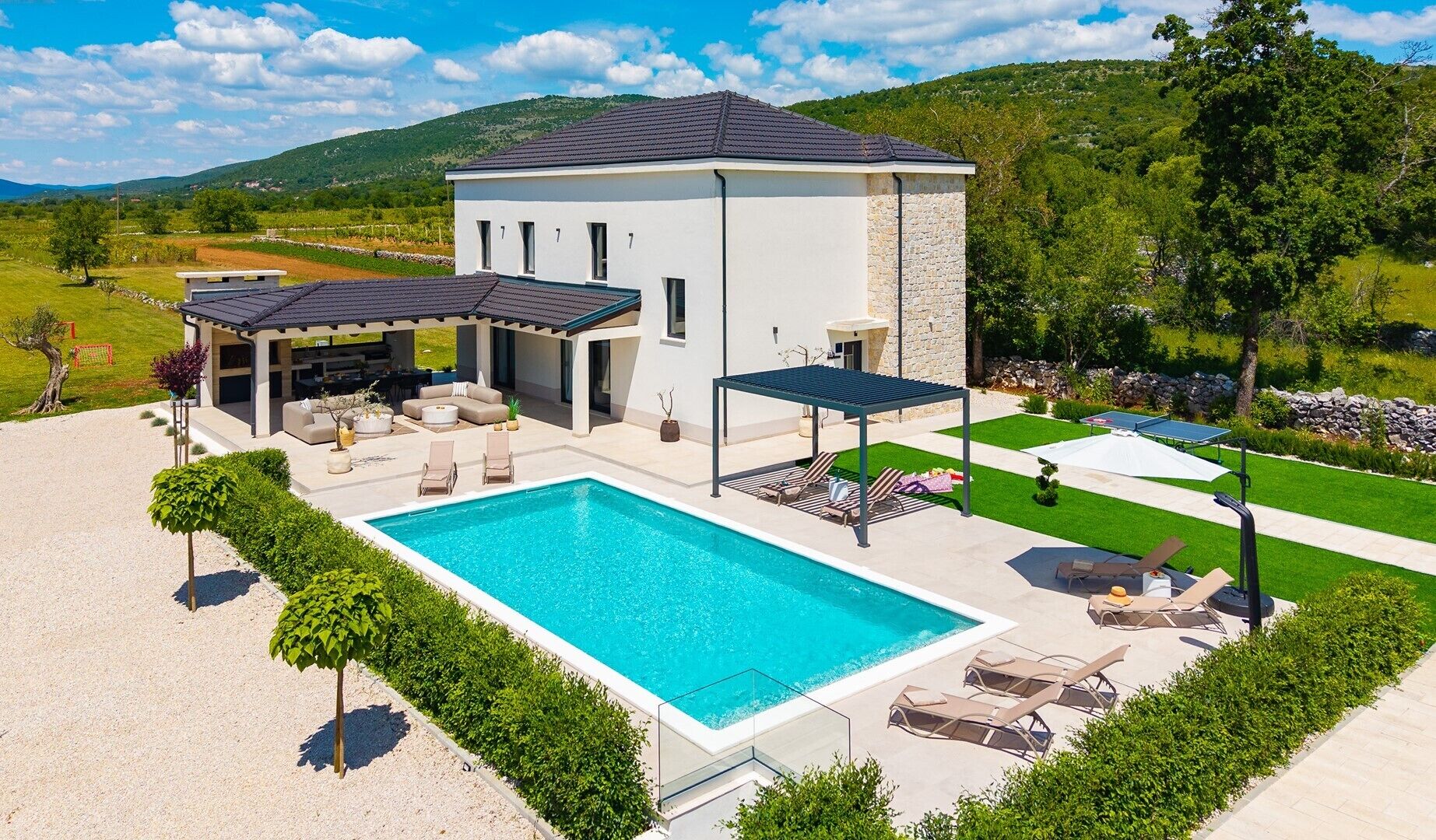 Ein modernes Haus mit Schwimmbad, Sitzgelegenheiten im Freien und einer überdachten Terrasse.