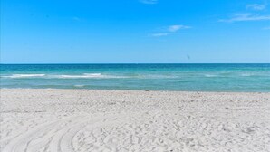 Een strand met helderblauw water en een zandkust.