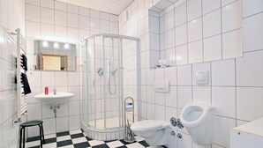 Une salle de bain avec un lavabo blanc, des toilettes, une douche et un carrelage noir et blanc à motifs carrés.