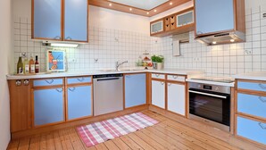 Une cuisine avec des meubles de rangement en bois, un lave-vaisselle et un four encastré.