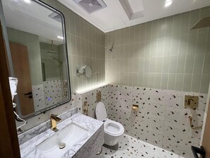 Een badkamer met een marmeren wastafel, toilet en douche.