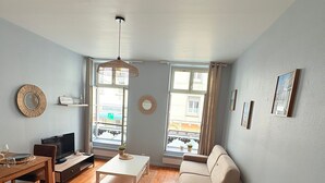 A living room with a sofa, a coffee table, a TV, and a dining area with a table and chairs.