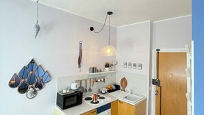 A compact kitchen with wooden cabinets, a microwave, a kettle, and a sink. - Ferraretto cosy studio for 2 in Rapallo (Rapallo)