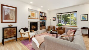 A spacious living room with a fireplace, comfortable seating, and large windows offering a view of the outdoors. - Rigden Retreat | Garage, Dog Friendly, Near Trails (Fort Collins)