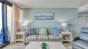 A living room with a sofa, two side tables, a coffee table, and a view of the ocean. - Oceanfront Two Bedroom, Two Bath Horizon East Condo (Garden City Beach)