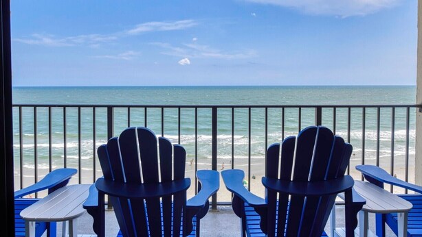 A balcony with chairs and tables overlooking a beach. - Oceanfront Two Bedroom, Two Bath Horizon East Condo (Garden City Beach)