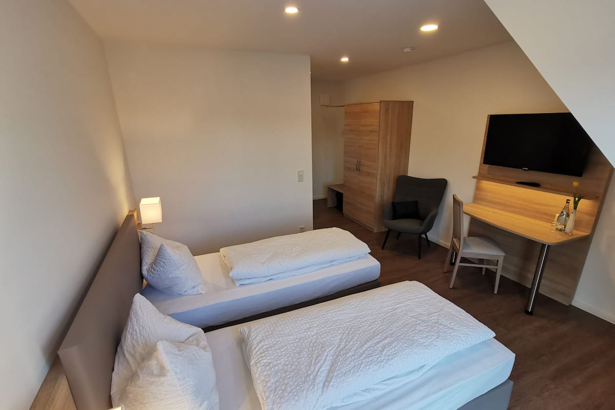 Une chambre d’hôtel avec deux lits, un bureau, une chaise, une télévision et une armoire.