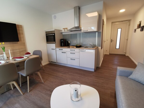 Un espacio habitable compacto con kitchenette, comedor y zona de estar.