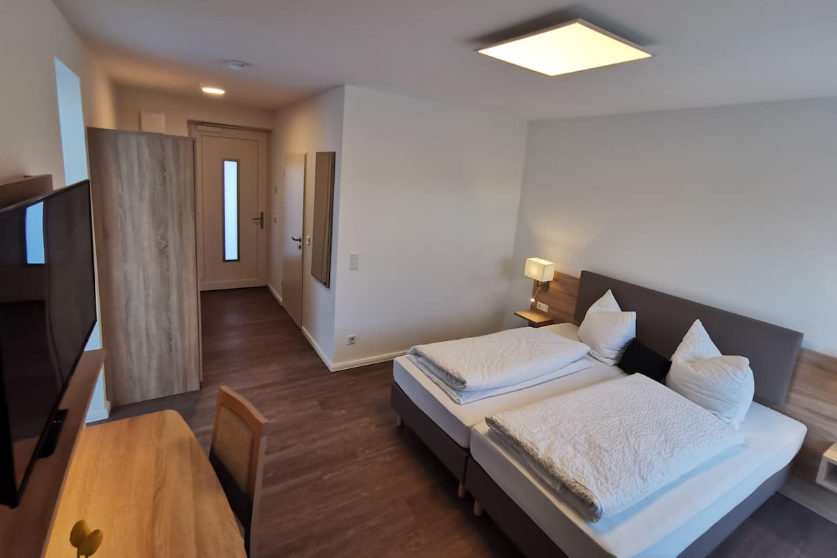 Une chambre d’hôtel équipée d’un lit, de tables de chevet, d’un bureau et d’une télévision.