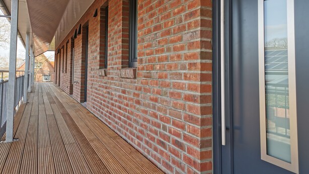 Un espace extérieur abrité, doté d’un mur en briques et d’un plancher en bois.