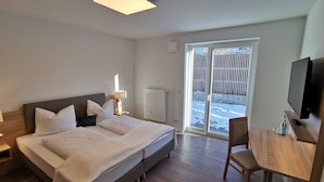 Une chambre d’hôtel équipée d’un lit, d’un bureau, d’une chaise, d’une télévision, d’une fenêtre et d’un radiateur.