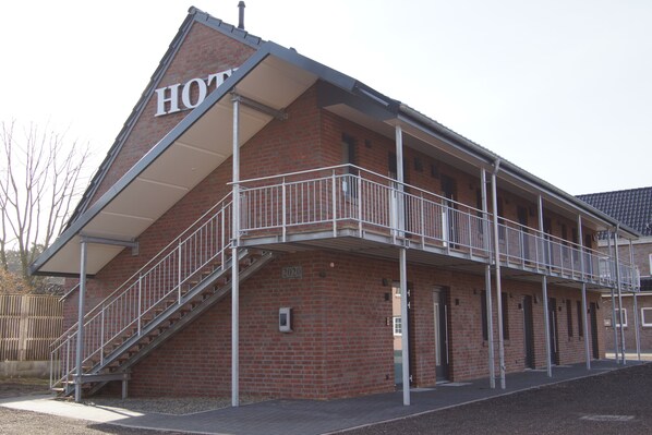A brick building with a balcony and a staircase leading to the entrance. - Hotel zur Erholung (Buxtehude)