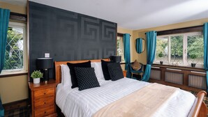 A bedroom with a large bed, a nightstand with a lamp, a dresser, and a window with curtains. - The Mayflower at Austerfield (Doncaster)