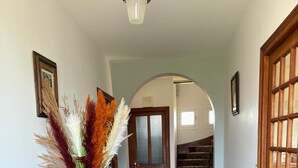 A hallway with a wooden bench, a vase with dried plants, and a door leading to a staircase. - Family home (Eymoutiers)