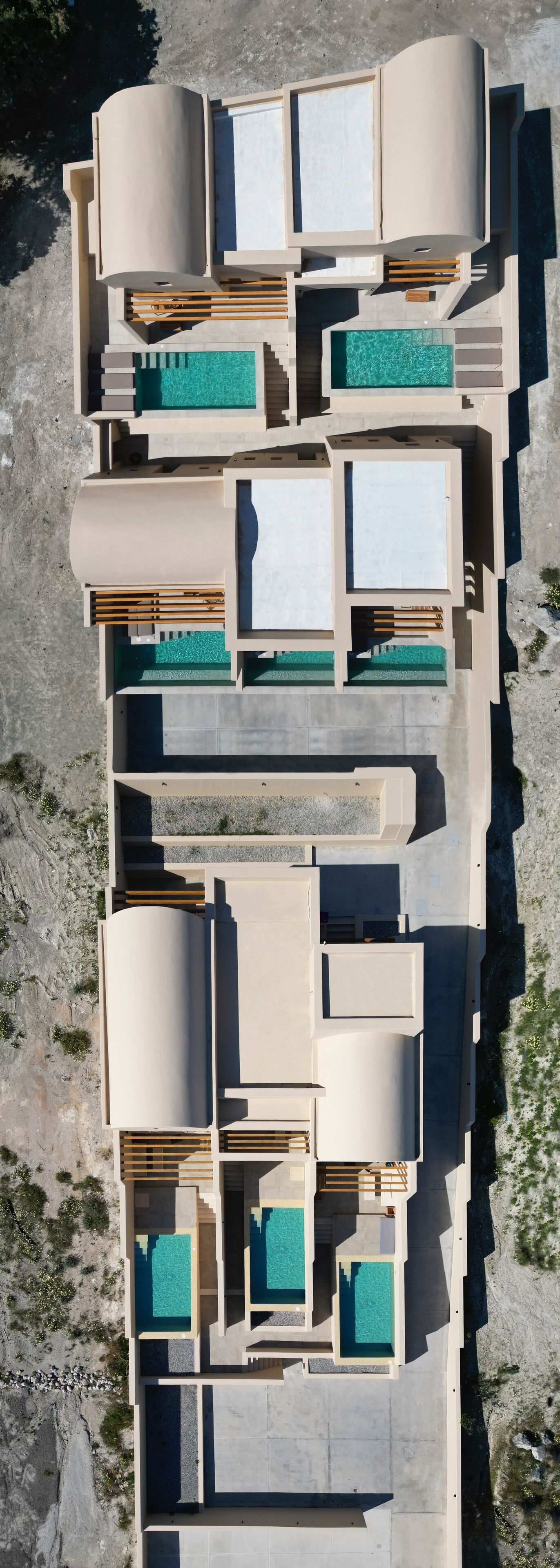 An aerial view of a modern resort with multiple swimming pools, outdoor seating areas, and a spacious layout.