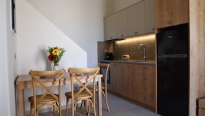 Una cocina moderna con armarios de madera, un refrigerador negro y un comedor con dos sillas de madera y un jarrón de flores.