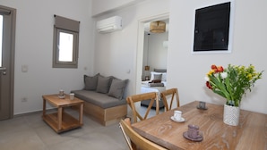 Un espacio habitable compacto con sofá, mesa de madera y zona de comedor.