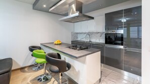 A modern kitchen with a central island, bar stools, and built-in appliances.