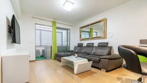 A modern living room with a sofa, coffee table, and a TV mounted on the wall.