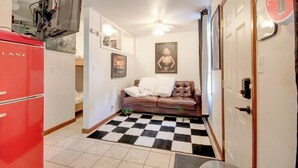 A compact living space with a checkered floor, a red appliance, a brown leather sofa, and a door with a Coca-Cola logo. - Private Guesthouse Retreat Near Kentucky Lake! (Dover)
