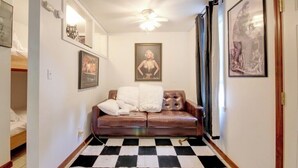 A hallway with a checkered floor, a brown leather sofa with white cushions, a ceiling fan, and framed pictures on the walls. - Private Guesthouse Retreat Near Kentucky Lake! (Dover)