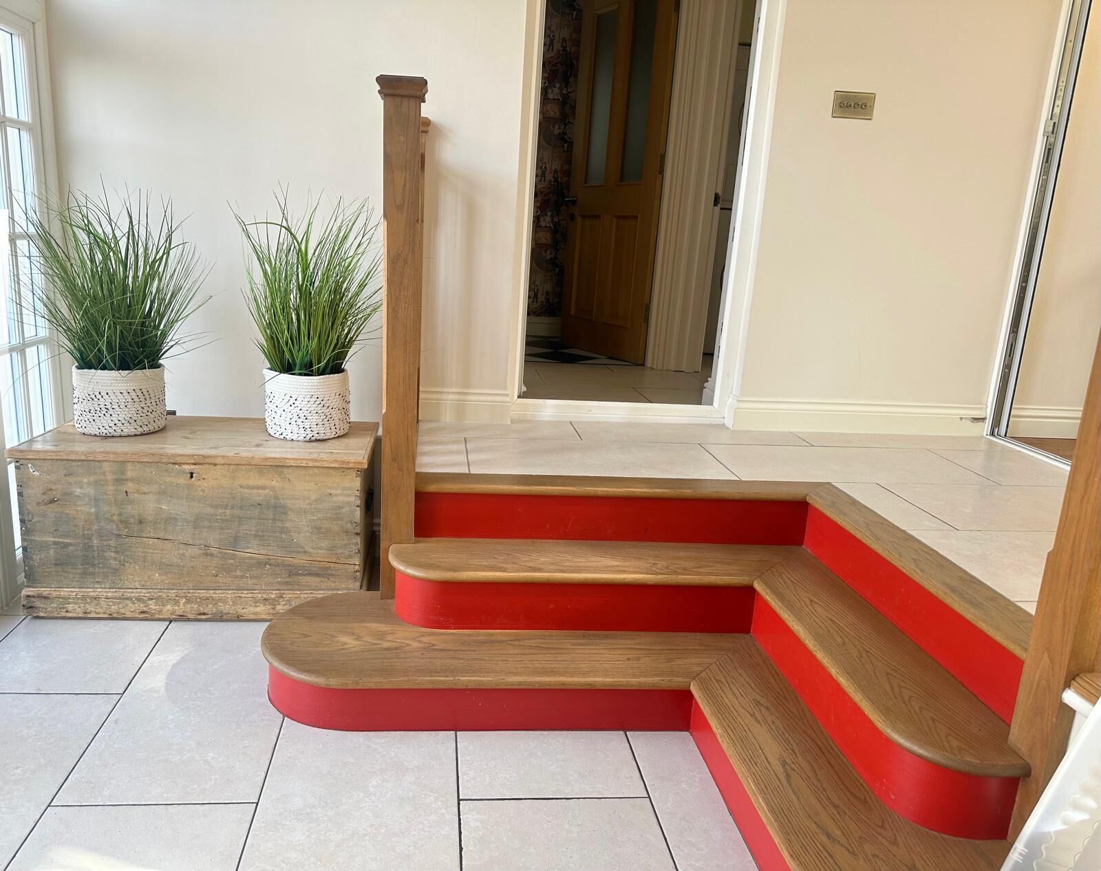 Un escalier avec des marches en bois et des contremarches rouges menant à une porte.