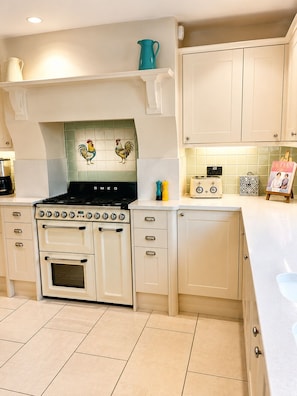 A kitchen with white cabinetry, a black stove, and a tiled backsplash.