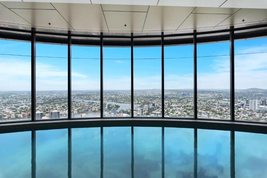 A panoramic view from a high-rise building with a glass floor, offering a clear view of the cityscape and river below.