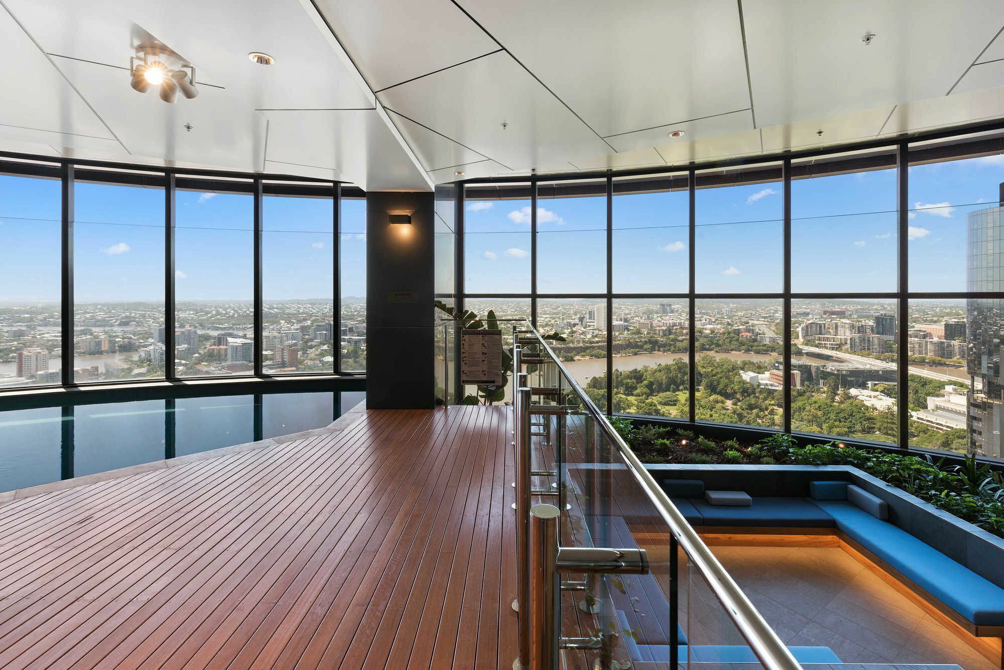 A high-rise building with a glass exterior, a wooden deck, and a seating area with a view of the city.