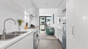 Une cuisine moderne avec des meubles blancs, des appareils en acier inoxydable et une vue sur l’espace de vie.