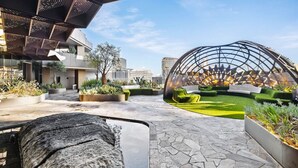 An outdoor area with a stone pathway, a rock feature, green planters, and a unique spherical structure. - Platinum Pad Westside Place, Balcony, Heated Pool, Gym, Sauna, Steam. (Melbourne)