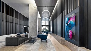 A modern interior with a central seating area, a large abstract painting, and a high ceiling with circular lighting. - Platinum Pad Westside Place, Balcony, Heated Pool, Gym, Sauna, Steam. (Melbourne)