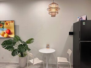 Una cocina moderna con sillas blancas, una planta en maceta, una mesa redonda y un refrigerador negro.
