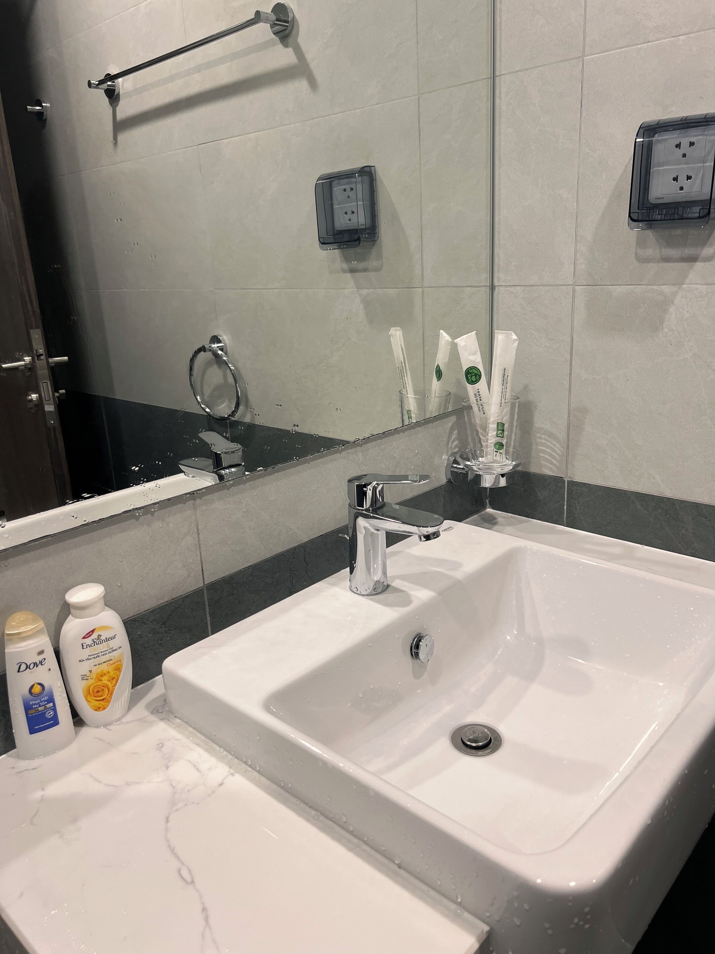 A bathroom with a white sink, a mirror, and toiletries.
