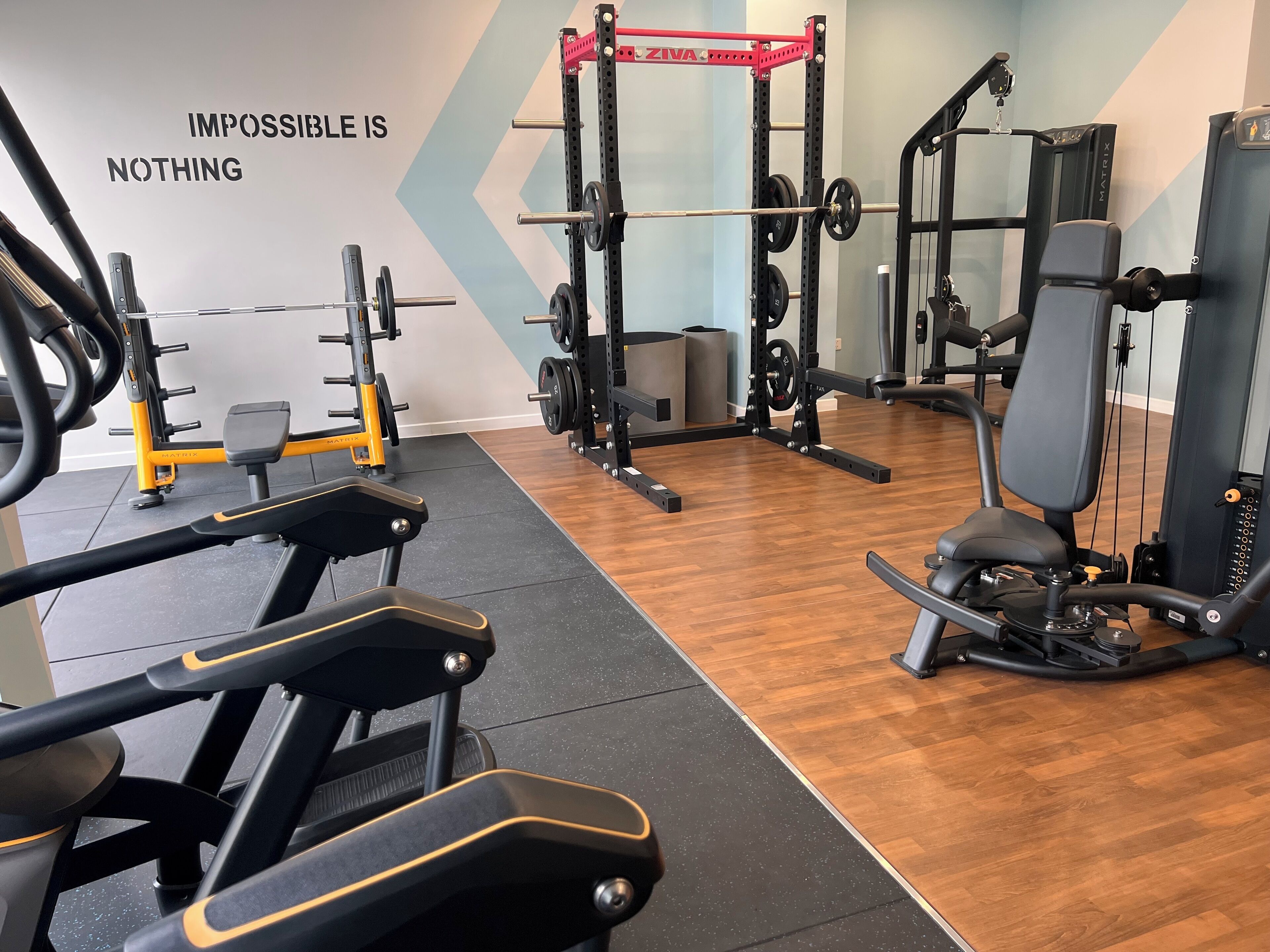 A gym with various exercise equipment, including treadmills, weight machines, and a squat rack.