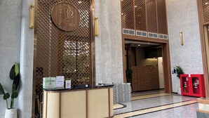 A reception area with a wooden reception desk, a large arched entrance, and a modern interior design. - Vinhomes Grand Park-The Beverly Hills (Ho Chi Minh City)