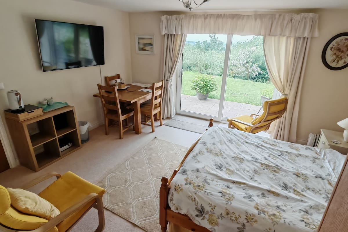 Une chambre à coucher avec un lit, un bureau, une chaise, un téléviseur et une fenêtre avec des rideaux.